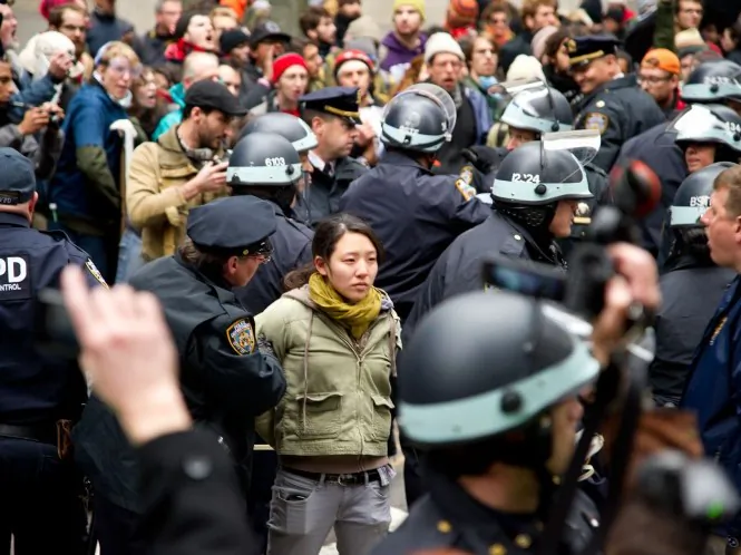 Police officers closely watch the protesters as they march on Wall Street in New York on Thursday. (Benjamin Chasteen/The Epoch Times)