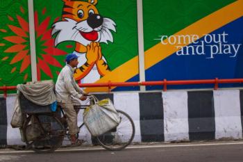 An Indian commuter cycles past a banner for the Commonwealth Games on September 23, 2010, in New Delhi, India. Delhi is scrambling to clean up the athletes' village following numerous complaints from officials. (Daniel Berehulak/Getty Images)