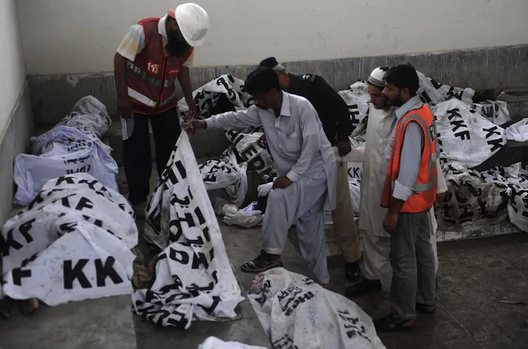 Pakistani policemen and rescuers identify the dead bodies of garment laborers who were killed after fire erupted at a factory in Karachi on Sept. 12. (Rizwan Tabassum/AFP/GettyImages)