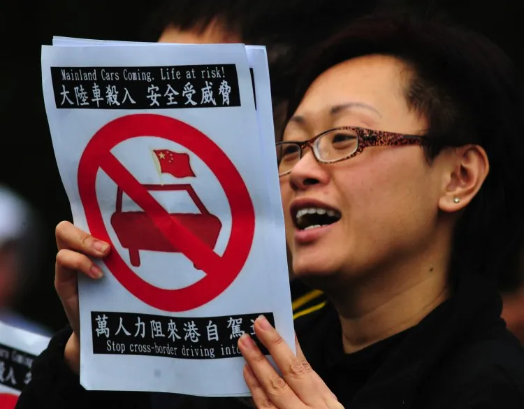 A woman holds a placard against allowing mainland Chinese drivers into Hong Kong at a demonstration in a park in Hong Kong on Feb 12. (Antony Dickson/AFP/Getty Images)
