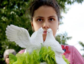 A young girl holds white doves as a symbol of peace during a commemorative ceremony in front of the U.S. Embassy in Ottawa (Samira Bouaou/The Epoch Times)