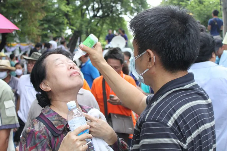 A supporter of the royalist group Pitak Siam has her eyes washed after being hit with tear gas fired by Thai police at the group’s rally site in Bangkok Saturday. (Cameron McKinley/The Epoch Times)
