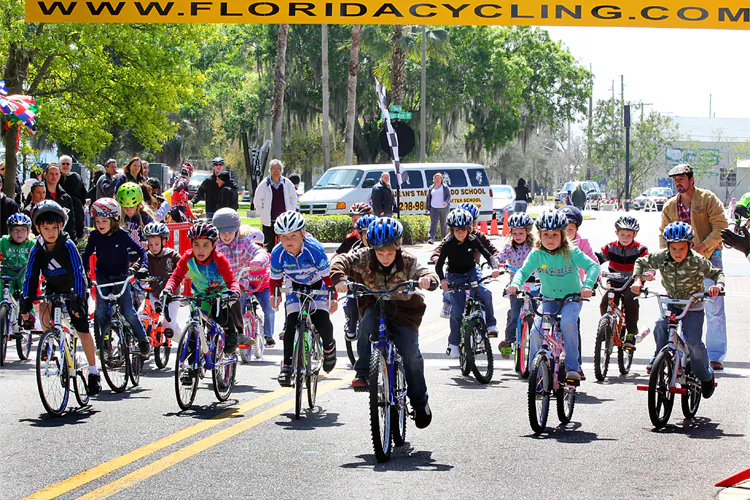 A couple of dozen children ages four to nine leave the starting line to begin the Chain of Lakes Cycling Classic Kids’ Race. (James Fish/The Epoch Times)