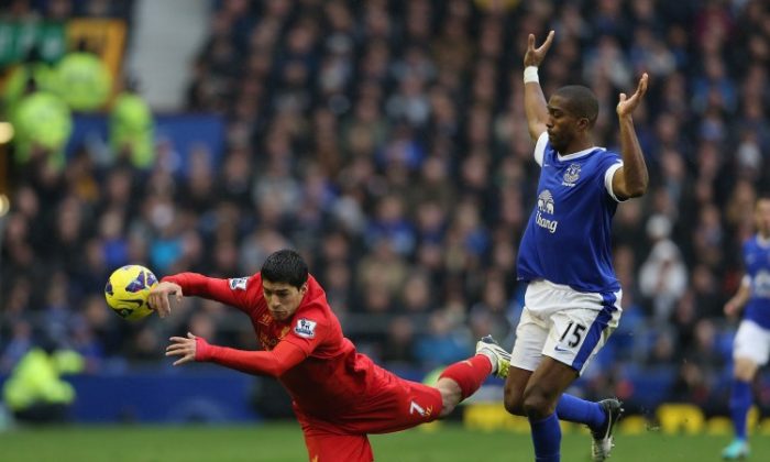Liverpool’s Luis Suarez (L) goes down in a challenge from Everton’s Sylvain Distin in Sunday’s Merseyside derby at Goodison Park. (Clive Brunskill/Getty Images)