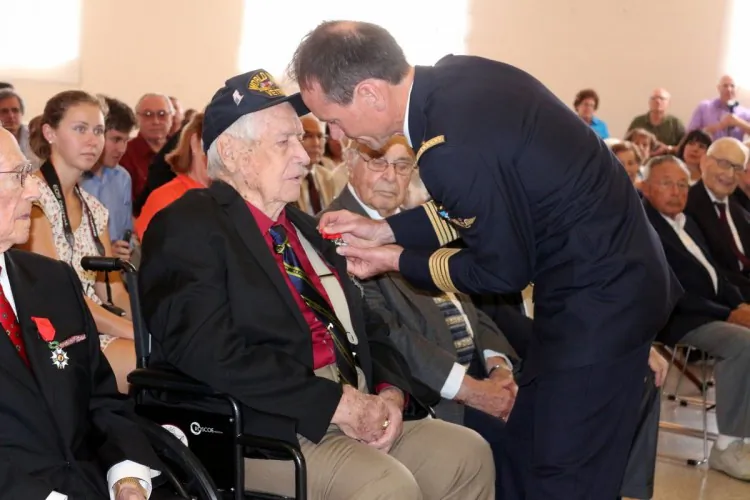 U.S. combat veteran Frank Alessi proudly wearing his Legion of Honor medal, holding a bottle of French Champagne to celebrate the event with his daughter (in red) Marlene Shitts, next to Alessi in flower shirt and hat is his French friend from Prades, himself a veteran of the Algerian War, Claude Rivoire. The woman in black is their friend Jeanne Marie Mangino and next to her in white is their friend Suzie Vitart, formerly of Paris now living in Lesureville in Boynton Beach. French people paid tribute to the courage and sacrifice of U.S. servicemen that landed in Normandy on D Day and fought to liberate France and Europe . (John Christopher Fine copyright 2013)