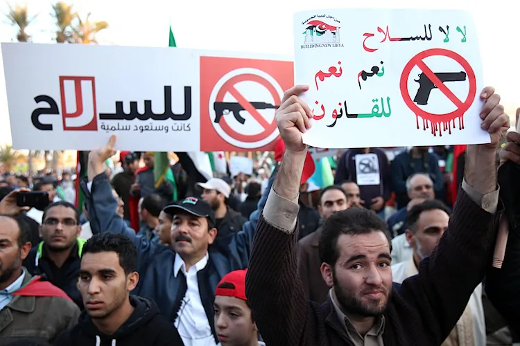 Libyan demonstrators hold a banner that reads in Arabic “No for arms, yes for law. … It was and it shall be peaceful again” during a protest calling for disarming militiamen in Tripoli’s landmark Martyrs Square on Dec. 9, 2011. (Mahmud Turkia/AFP/Getty Images)