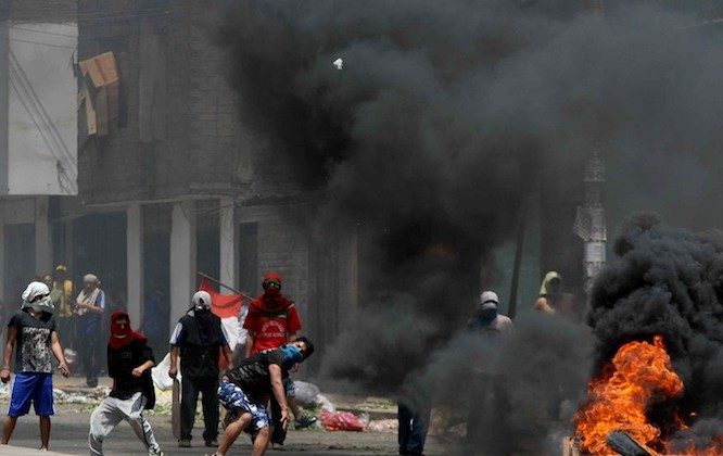 Protesters burn tires and throw objects during clashes with the police in Lima, on Oct. 27, 2012. Two people were killed during clashes while the police relocated a crowded wholesale food market in Lima, officials said. The fighting began when municipality workers placed concrete blocks at the entrance of La Parada market to prevent trucks from entering, leading traders to hurl stones in protest. (STR/AFP/Getty Images)