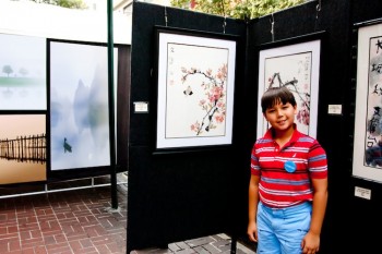 YOUNG TALENT: Christopher Elson, 9, stands in front of his and his father Paul Elson's paintings to the left at the Washington Square Park Outdoor Art Exhibit Sunday afternoon. (Tara MacIsaac/The Epoch Times) YOUNG TALENT: Christopher Elson, 9, stands in front of his and his father Paul Elson's paintings to the left at the Washington Square Park Outdoor Art Exhibit Sunday afternoon. (Tara MacIsaac/The Epoch Times)
