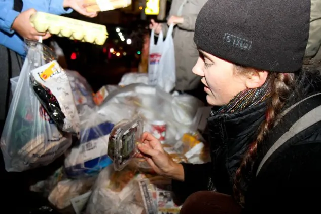 Cindy Rosin pulls food out of a garbage bag in front of a grocery store on Sixth Avenue and 12th Street. (Tara MacIsaac/The Epoch Times)