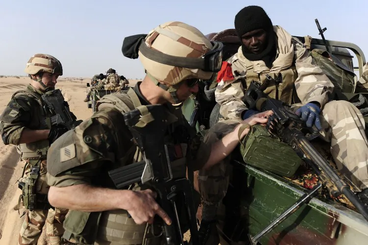 A French soldier (L) looks at the weapon of a Malian soldier as they enter Bourem, northen Mali on Feb. 17, 2013. The head of a European Union training force has called for better equipment for the "impoverished" Malian army, as human rights groups caution oversight is necessary in empowering the army. (Pascal Guyot/AFP/Getty Images)