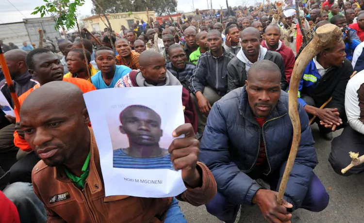A miner carries a photo of a killed miner as thousands of striking workers singing and carrying sticks march on a South African mine in Marikana on Sept. 5 as police were accused of shooting miners in cold blood during a crackdown that killed 34. (Alexander Joe/AFP/GettyImages)