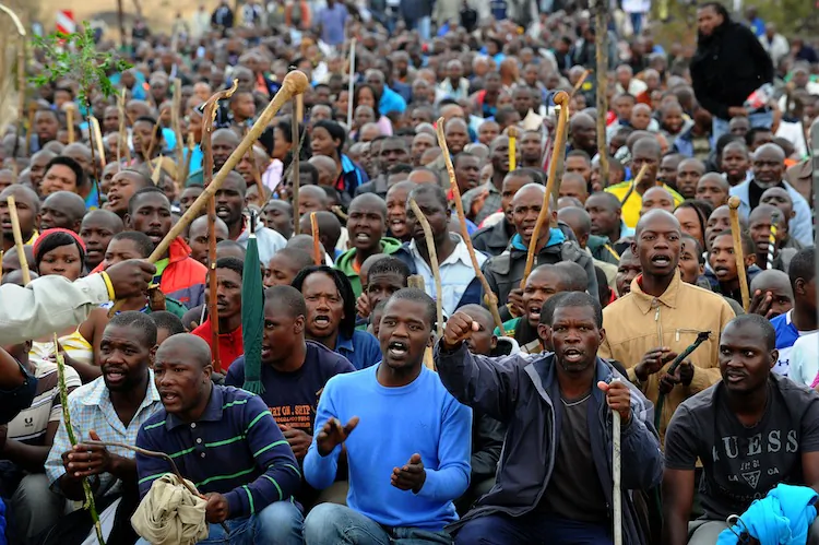 Thousands of striking workers singing and carrying sticks march on a South African mine in Marikana on Sept. 5. Police were accused of shooting miners in cold blood during a crackdown that killed 34. (Alexander Joe/AFP/Getty Images)