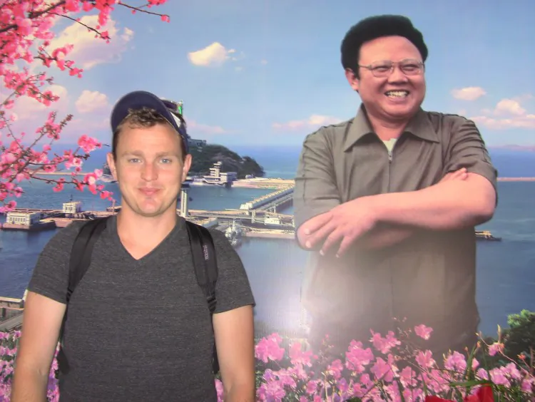 Rob Montz, a documentary filmmaker, in 2012 stands in front of a propaganda portrait of Kim Jong-Il, the son of the founder of the North Korean regime Kim Il-sung. (Courtesy of Rob Montz)