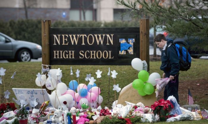 A student brings flowers to a makeshift memorial for the victims of the Sandy Hook Elementary School shooting at the entrance of Newtown High School Dec. 18, 2012 in Newtown, CT. (Brendan Smialowski/AFP/Getty Images)