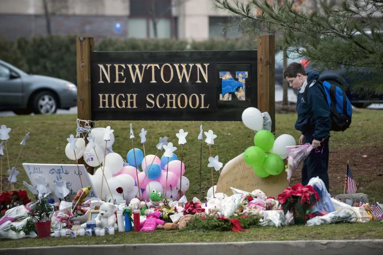 A student brings flowers to a makeshift memorial for the victims of the Sandy Hook Elementary School shooting at the entrance of Newtown High School Dec. 18, 2012 in Newtown, CT. (Brendan Smialowski/AFP/Getty Images)