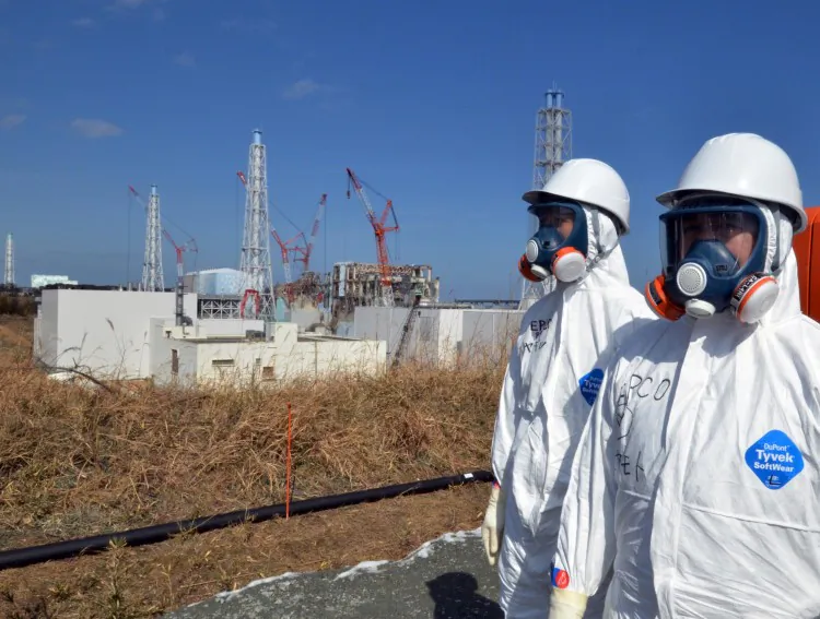 Workers in safety gear stand near the stricken Fukushima Daiichi nuclear power plant in this recent photo. The U.S. will examine international efforts in securing nuclear materials at a conference in Seoul that begins March 26. (Yoshikazu Tsuno/AFP/Getty Images)