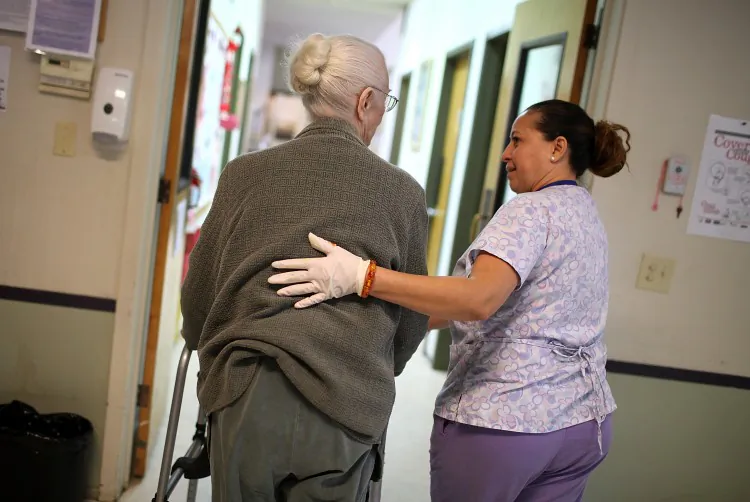 A program assistant at an adult care center helps her elderly patient. Cuts in cost-of-living adjustments impact retirees, making it more of a challenge to pay for health care services. (Justin Sullivan/Getty Images)