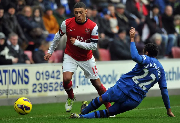 Arsenal’s Alex Oxlade-Chamberlain skips past Wigan defender Jean Beausejour in Barclays Premier League action in Wigan on Saturday, Dec. 22, 2012. (Paul Ellis/AFP/Getty Images)