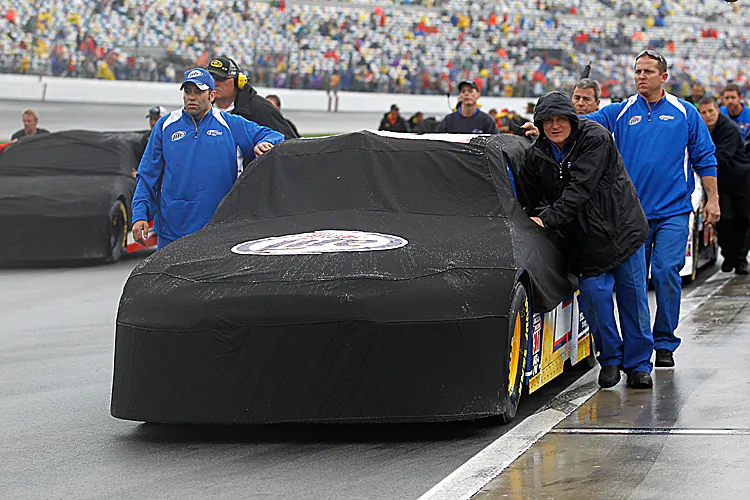 Crews push covered cars off the track so jet-dryers can try to cope with the rain at the Daytona International Speedway. The Daytona 500 was postponed until Monday. (Todd Warshaw/Getty Images for NASCAR)