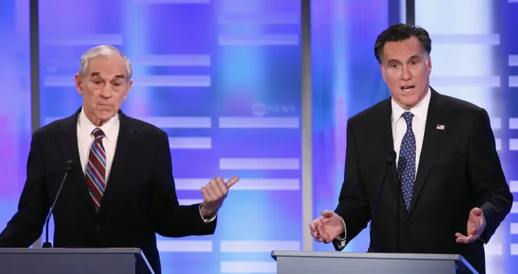 Republican presidential candidate Rep. Ron Paul (R-Tex) (L) gestures towards fellow candidate and former Massachusetts Gov. Mitt Romney in the ABC News, Yahoo! News, and WMUR Republican Presidential Debate at Saint Anselm College in Manchester, N.H., Jan. 7. The GOP contenders are in the final stretch of campaigning for the New Hampshire primary, to be held Tuesday Jan. 10. (Win McNamee/Getty Images)