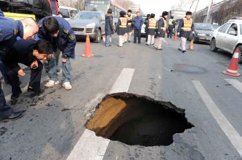 Chinese workers inspect a sinkhole in a street in Beijing on Feb. 8. Sinkholes are known geological phenomena that usually occur predominantly in areas that have been heavily mined or on reclaimed land. (AFP/Getty Images ) Chinese workers inspect a sinkhole in a street in Beijing on Feb. 8. Sinkholes are known geological phenomena that usually occur predominantly in areas that have been heavily mined or on reclaimed land. (AFP/Getty Images )