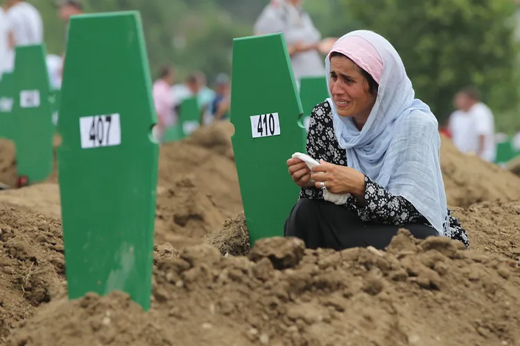 A Muslim woman weeps at the fresh grave of one of 613 newly-identified victims of the 1995 Srebrenica massacre during a mass funeral July, 11, 2011 attended by tens of thousands of mourners at the Potocari cemetery and memorial near Srebrenica in Potocari, Bosnia and Herzegovina. (Sean Gallup/Getty Images)