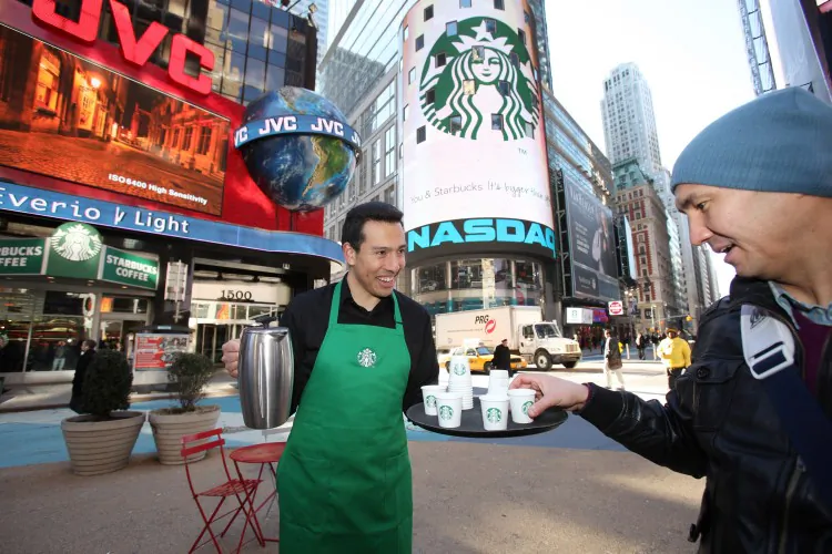 A barista joins the morning rush-hour crowd to distribute samples of the new Starbucks Tribute Blend™ outside a store in New York’s Times Square, one of only four stores globally showcasing the new logo in celebration of Starbucks 40th anniversary. (Courtesy of Starbucks Corporation)