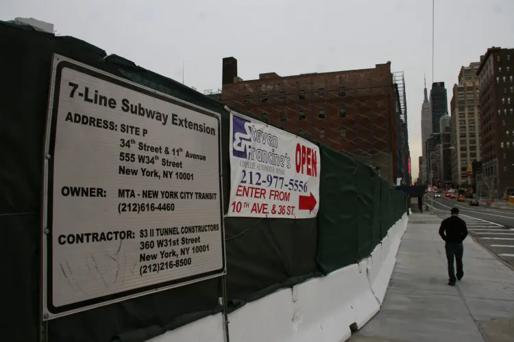 A sign for the West 7-Line Subway Extension, next a sign letting customers know Steven Francine's auto shop is still open, with an alternative entrance. (Zack Stieber/The Epoch Times)