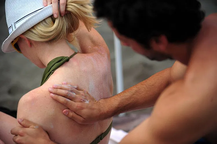 A sunbather applies sunscreen onto another in this file photo. The FDA announced it is delaying the release of new regulations for sunscreen manufacturers until December. (Martin Bernetti/AFP/Getty Images)