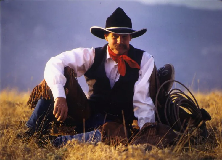 Cowboy poet and author Waddie Mitchell sits outdoors for a photograph with his gear. Mitchell often tours with cowboy balladeer Don Edwards, and is helping preserve the culture of cowboy poetry. (Photo by C. West)