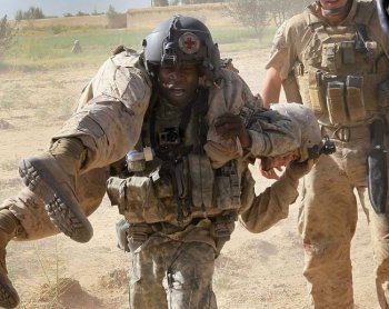 U.S. Army flight medic Sgt. Tyrone Jordan, attached to Dustoff Task Force Shadow of the 101st Combat Aviation Brigade, carries a Marine wounded by an explosive blast to a MEDEVAC helicopter near Marja, Afghanistan. (Scott Olson/Getty Images)