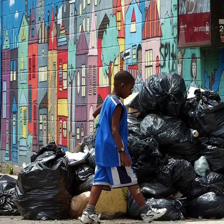 A youth walks past a pile of dumped garbage bags during a garbage collection strike in Toronto in July 2002. Canada produces the most garbage per capita when compared to other developed countries, according to a new report. (J.P. Moczulski/AFP/Getty Images)