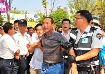 Police arrest a man attacking participants of the 'Quit the CCP' parade held in Ansan City, South Korea. (Jin Guohuan/The Epoch Times) Police arrest a man attacking participants of the 'Quit the CCP' parade held in Ansan City, South Korea. (Jin Guohuan/The Epoch Times)