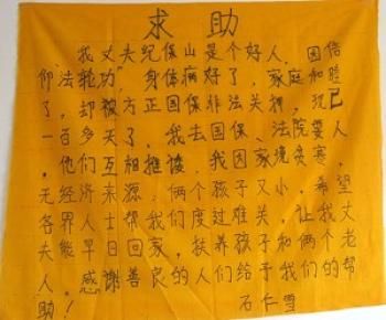 A woman from Fangzheng County writes her appeal on a piece of yellow cloth as she begs for food with her infant after her family was torn apart by persecution. (The Epoch Times)
