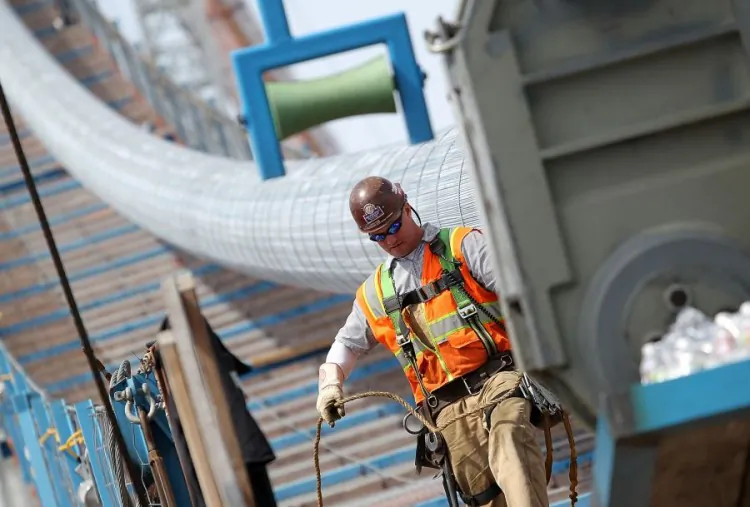 An ironworker walks by the main cable of the San Francisco-Oakland Bay Bridge Self-Anchored Suspension Span (SAS) after a hydraulic compaction device passes over it on May 2, in Oakland, Calif. The main cable installation of the Self-Anchored Suspension Span is nearly complete as crews finish up compacting nearly one mile of cable that is comprised of 137 individual strands. The bridge has been under construction since 2002 with an estimated price tag of $6.3 billion and will have the world's tallest Self-Anchored Suspension tower once completed. (Justin Sullivan/Getty Images)