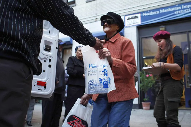 A person receives free milk from the Milk from the Heart program, which makes weekly deliveries to Washington Heights and 12 other locations in Manhattan and the Bronx on Oct. 6 in New York City. The Census Bureau officially defines poverty as a family of four with an income of $22,314. That measure has been criticized as unrealistic. (Spencer Platt/Getty Images)