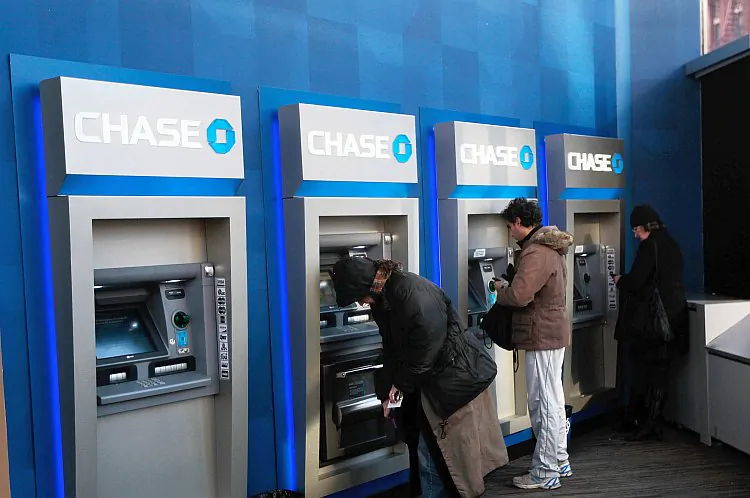 People use ATMs at a Chase branch bank in New York City. Banks are important for the economy but their lending practices lead to inequality. (Chris Hondros/Getty Images)