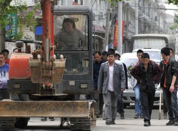 Chinese authorities carry sticks as they prepare to stand guard before workers demolish houses which are claimed illegal by local government in Wuhan, central China's Hubei Province on May 7, 2010. Land seizures have been a problem for years in China and forced evictions have not been uncommon. (AFP/Getty Images)