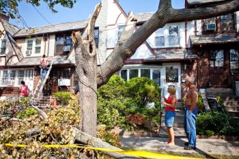Donna-Marie Goedtel and neighbour, Teddy Cleanthes, look on as workers repair damage done to Goedtel's Forest Hills home. (The Epoch Times)