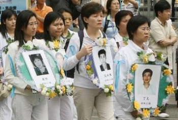 Women hold photos of Falun Gong practitioners who have died in Chinese prisons during a ten year persecution by the Chinese regime. (Mike Clarke/AFP/Getty Images)