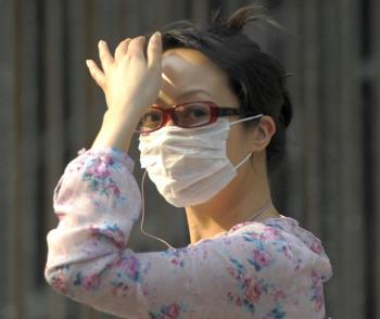 A woman wearing a face mask walks along a street in Beijing on May 5, 2009. Influenza H1N1 is spreading rapidly throughout all 31 provinces in mainland China. (Liu Jin/AFP/Getty Images)