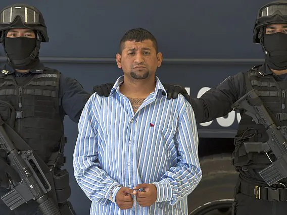 Mexican Federal police personnel escort David Rosales Guzman, aka "Commander Devil", alleged member of the Gulf cartel, during his presentation to the press at the Police Command Centre in Mexico City on September 02, 2012. According to the Mexican authorities , Rosales Guzman was in charge of the illegal drug trafficking In Monterrey, north Mexico. (Omar Torres/AFP/GettyImages)