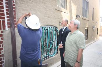 Borough President Marty Markowitz (R) views the installation of a new wireless water meter at his home.  (Hannah Cai/The Epoch Times)
