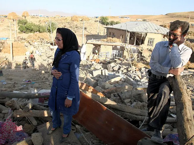 An Iranian man and woman stand on top of the rubble of their destroyed house in the village of Baje-Baj, near the town of Varzaqan, on August 12, 2012. (Atta Kenare/AFP/GettyImages)