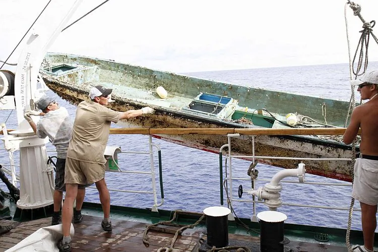 Crew from the Russian ship STS Pallada prepare to hoist a Japanese fishing boat on board. The Pallada came upon the boat floating among debris from the Japanese tsunami on its homeward voyage from Honolulu to Vladivostok in September. (Courtesy of Pallada)