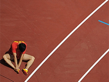 China's Xiang Liu examines his foot, injured in the first round of the men's 110m hurdles. (Christophe Simon/AFP/Getty Images) China's Xiang Liu examines his foot, injured in the first round of the men's 110m hurdles. (Christophe Simon/AFP/Getty Images)