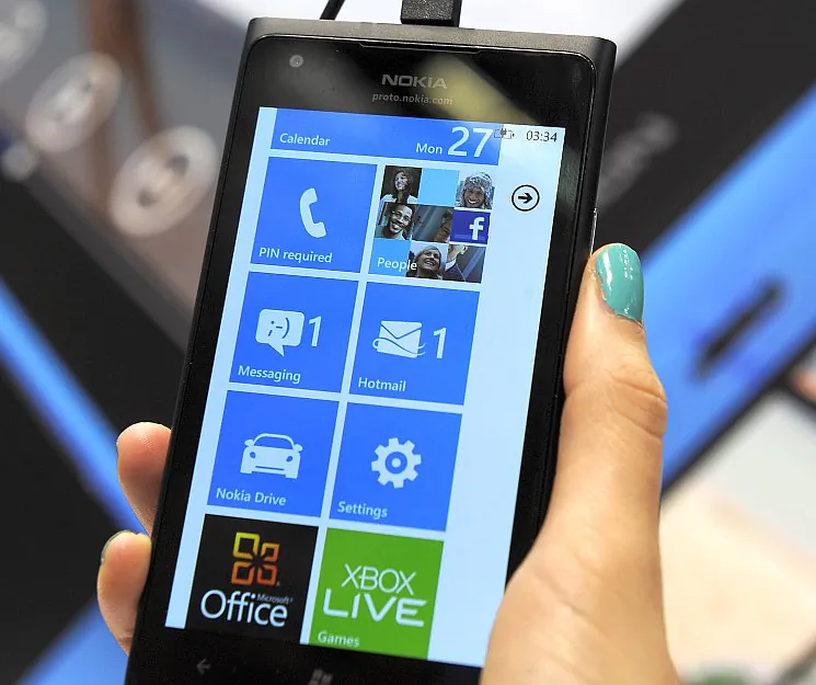 A hostess holds the Nokia Lumia 900 mobile phone at the 2012 Mobile World Congress in Barcelona, Feb. 27. On Sunday, the smartphone, which runs on Microsoft's Windows Phone operating system, will launch in the United States on the AT&T network. (Lluis Gene/AFP/Getty Images)