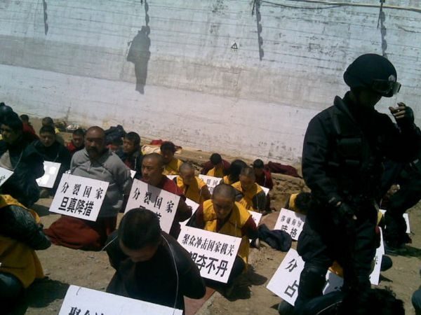 Tibetan monks on their knees, hands tied behind their backs