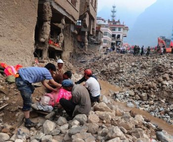 Surviving residents cover the body of a deceased relative resting on a makeshift stretcher amid the rubble of landslide devastation as rescue efforts continue in Zhouqu on August 11, in northwest China's Gansu province. (Frederic J. Brown/Getty Images )