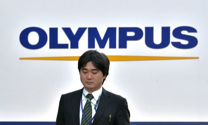 A businessman walks past a showroom of the troubled Japanese optical company Olympus in Tokyo on Jan. 10. Scandal-hit Olympus said it was suing 19 current and former executives for a combined US$215 million in damages relating to a massive investment cover-up. (Yoshikazu Tsuno/AFP/Getty Images)